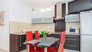 Una cocina moderna con una mesa de comedor, sillas rojas, microondas y refrigerador.
