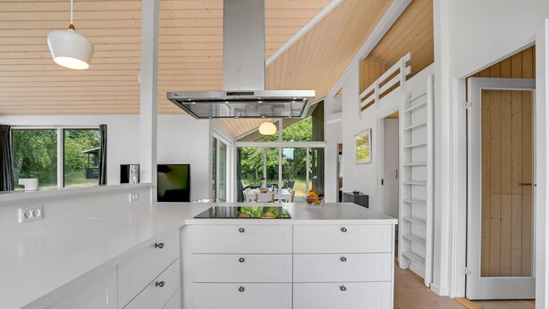 A modern kitchen with a central island, white cabinetry, and a large window offering a view of the outdoors. - Nice home in Jægerspris with kitchen (Jægerspris)