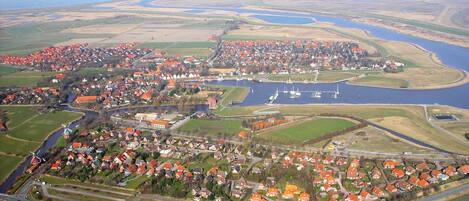 Luchtbeeld van een kustplaatsje met rode daken, een jachthaven en een rivier.
