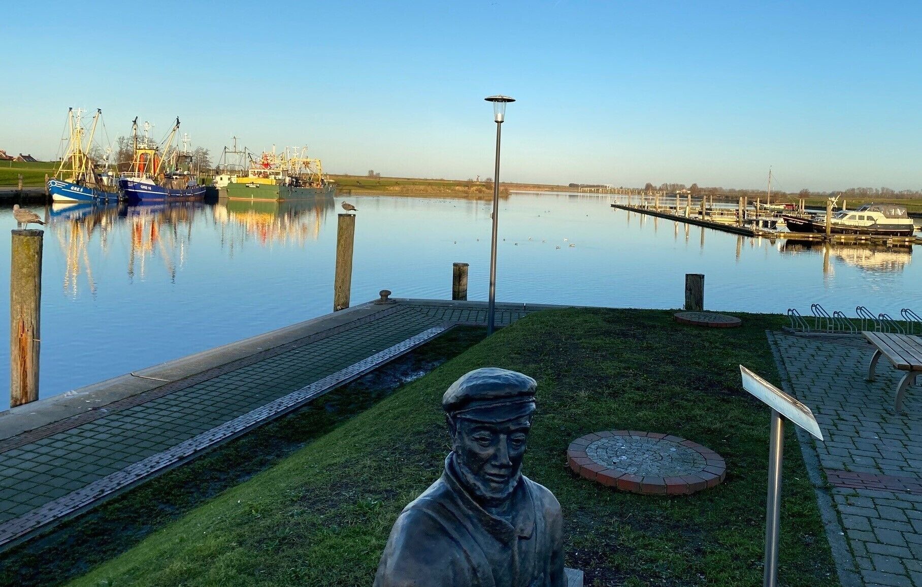 A marina with boats, a statue, and a lamp post.