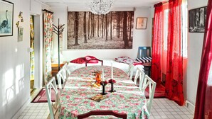 A dining area with a floral tablecloth, white chairs, and a forest-themed wall mural. - Pet friendly home in Hörby with WiFi (Hörby)