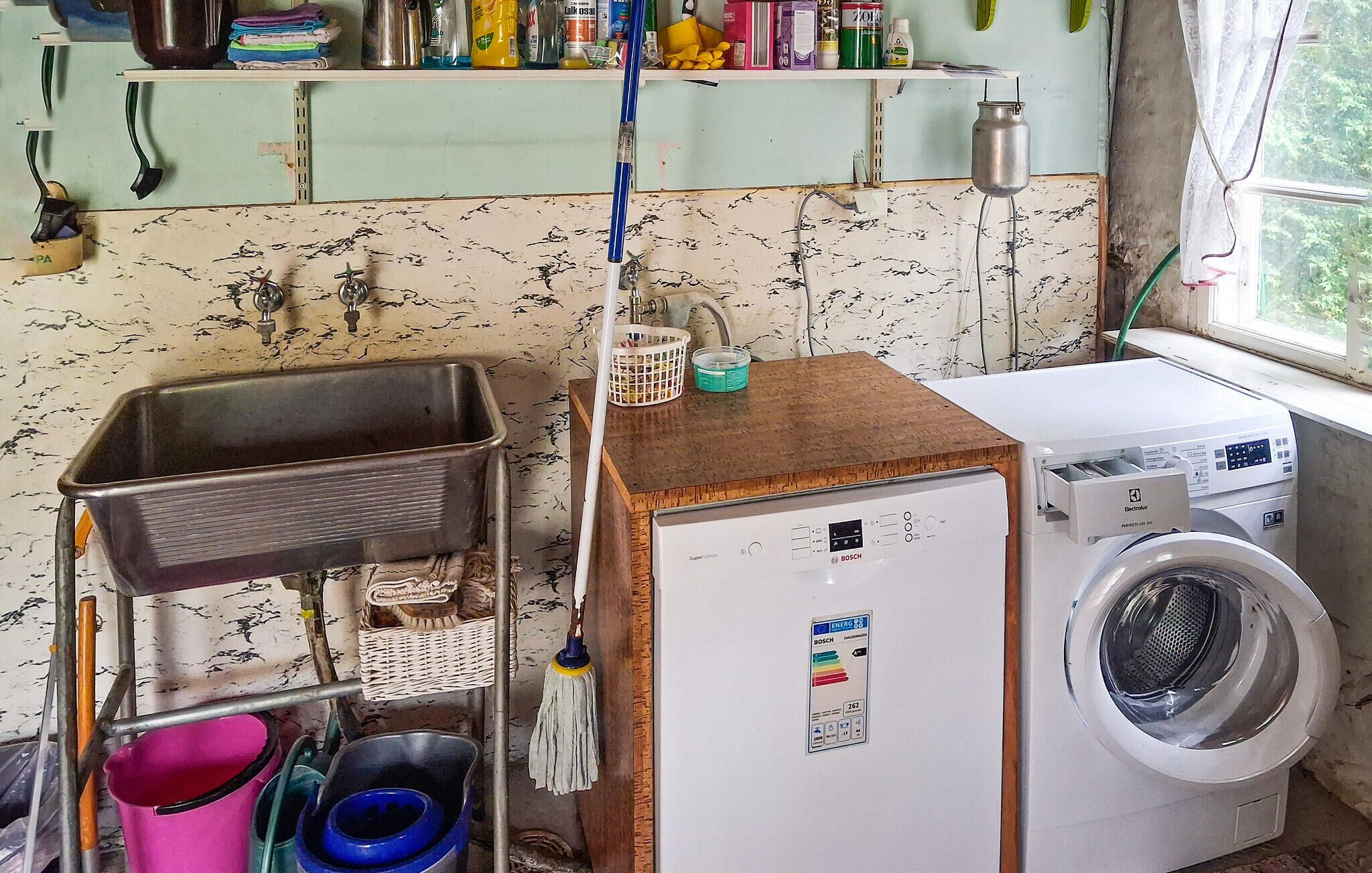 A compact laundry area with a washing machine, a small sink, and a shelf with various items.