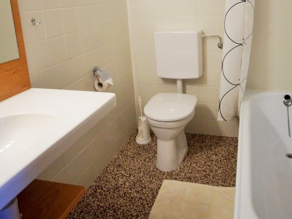 Ein Badezimmer mit Toilette, Waschbecken und Badewanne, alles in Weiß.