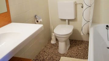 Ein Badezimmer mit Toilette, Waschbecken und Badewanne, alles in Weiß.