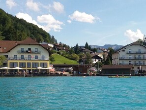 Ein Hotel direkt am Wasser mit mehreren Gebäuden, einem Steg und einer Bergkulisse im Hintergrund.