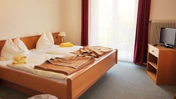 Ein Hotelzimmer mit Bett, Fernseher, Schreibtisch und einem fenster mit Vorhängen.