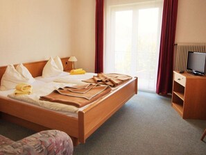 Ein Hotelzimmer mit Bett, Fernseher, Schreibtisch und einem fenster mit Vorhängen.
