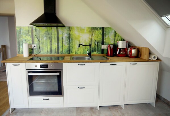 A kitchen with a built-in oven, a sink, and a coffee maker.