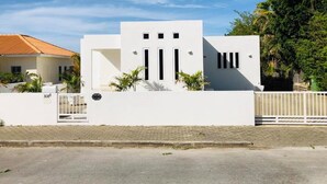A modern white building with a flat roof, a gated entrance, and a paved driveway. - Villa Brakkeput 308 (Jan Thiel)