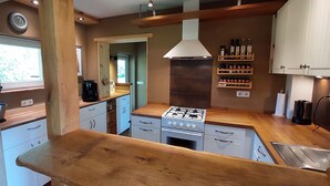 Una cocina compacta con encimeras de madera, estufa a gas, armarios blancos y horno integrado.