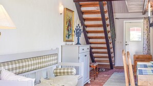 Une pièce chaleureuse avec un radiateur blanc, un banc, un escalier en bois et une porte dotée d’une fenêtre.