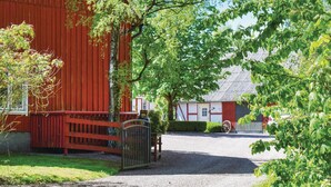 Une grange rouge avec un chemin de gravier menant à une maison blanche dont le toit est gris.