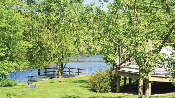 Une vue sur le lac, avec un quai en bois, un bateau et un kiosque.