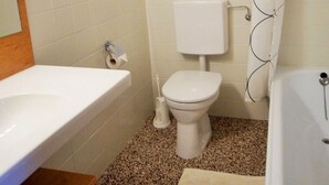 Une salle de bain avec des toilettes blanches, un lavabo blanc et une baignoire.