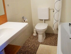 Ein Badezimmer mit Toilette, Waschbecken und Badewanne, alles in Weiß.