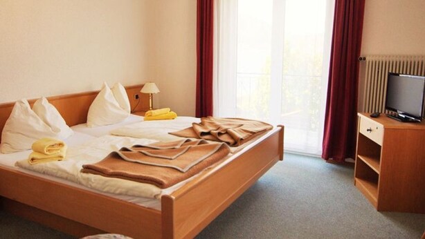 Une chambre d’hôtel avec un lit, une télévision, un bureau et une fenêtre avec des rideaux.