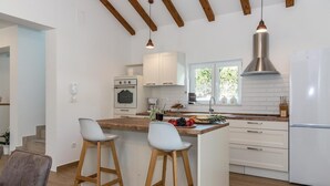A modern kitchen with white cabinetry, a stainless steel range hood, and a central island with stools. - Gorgeous home in Sibenik (Sibenik)
