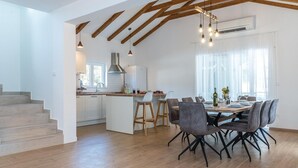 A modern kitchen with white cabinets, a central island, and wooden beams on the ceiling. - Gorgeous home in Sibenik (Sibenik)
