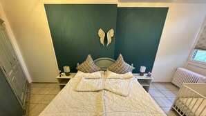 Ein Schlafzimmer mit einem Bett, zwei Nachttischen, einer Kommode, einem Heizkörper und einem Fenster.