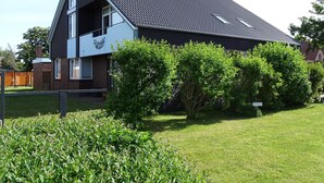 Ein modernes, zweistöckiges Haus mit Satteldach, sichtbarem Dachboden und einem umzäunten Garten.