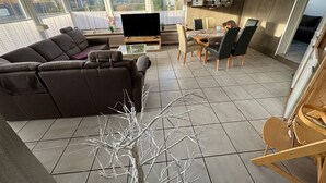 Ein modernes Wohnzimmer mit einer Eckcouch, einem Esstisch mit Stühlen und einem Fernseher.