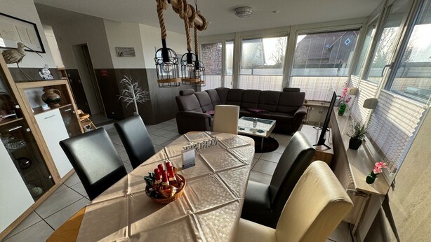 Ein modernes Wohnzimmer mit Esstisch, Sofas und Küchenzeile.