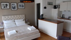 Una habitación de hotel moderna con una cama grande, una pequeña cocina y una mesa de comedor.