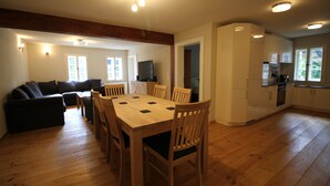 Eine moderne Küche mit weißen Schränken, einem eingebauten Backofen und einem Essbereich mit Holztisch und Stühlen.