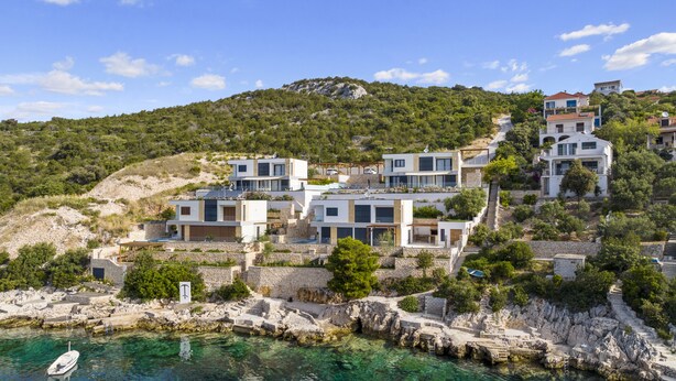 Una propiedad costera con arquitectura moderna, muros de piedra y una vista despejada del mar.