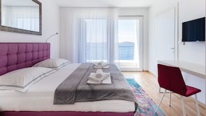 Habitación de hotel moderna con una cama grande, un escritorio y vistas al mar.