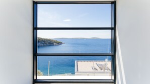 Una ventana con vista a un mar tranquilo y una isla distante.