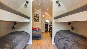Een compacte, moderne kamer met twee bedden, een kitchenette en een kleine eethoek.