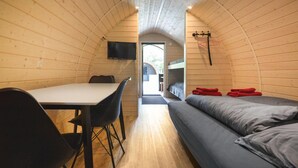 Een kleine kamer met een stapelbed, een tafel met stoelen en een aan de muur bevestigde televisie.