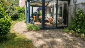 Une véranda avec un toit en verre, un chemin de jardin et un espace salon extérieur.