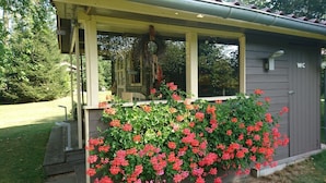 A small, single-story building with a porch and a flower box filled with red flowers. - In the middle of nature -Lavender hut- 9m² for 1-2 persons at Hilkenberg (Bodenfelde)