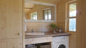 A compact wooden cabin with a built-in washing machine, a sink, and a mirror above it. - In the middle of nature -Lavender hut- 9m² for 1-2 persons at Hilkenberg (Bodenfelde)
