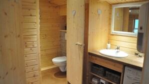 Ein Badezimmer einer Holzhütte mit Toilette, Waschbecken und Spiegel über dem Waschbecken.