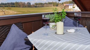 A balcony with a table set for two, featuring two wine glasses, a candle, and a potted plant. - Ferienwohnung "Meine Kleine Auszeit", 50 qm, Dachgeschoss, 1separates Schlafzimmer (Höslwang)