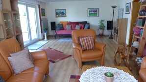 A living room with a sofa, armchairs, a coffee table, and a bookshelf. - Well-kept apartment in the Eifel. (Lissendorf)