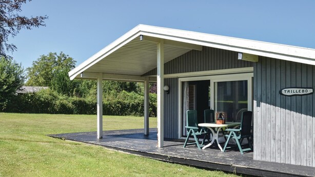 En liten, envåningsbyggnad med en överbyggd veranda och en skylt med texten ”TRILLEBO”.