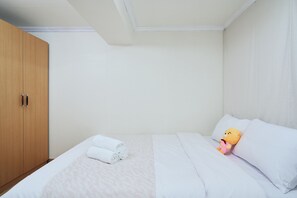 Ein Schlafzimmer mit einem Bett, einem Holzschrank und einem Stofftier auf dem Bett.