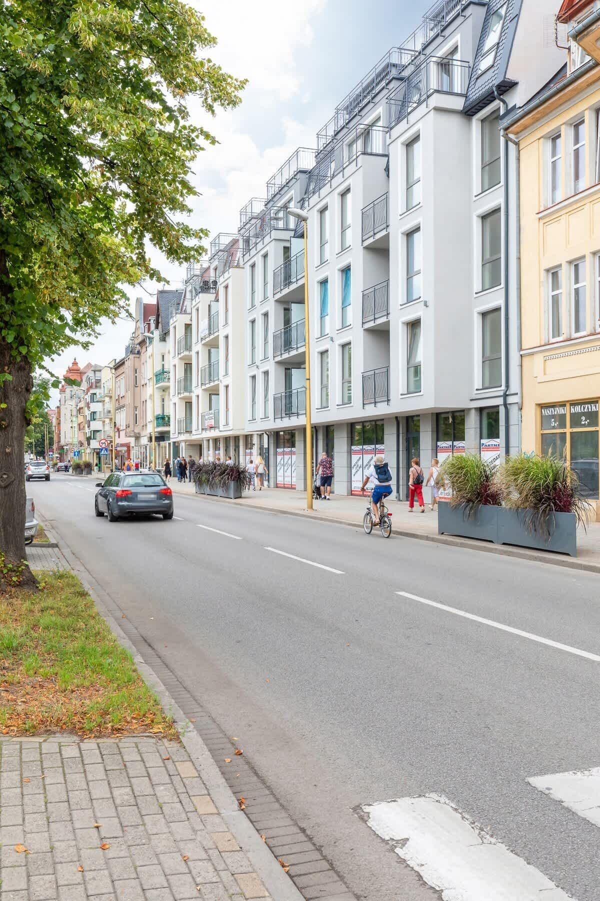 A street with modern buildings, a cyclist, and pedestrians.