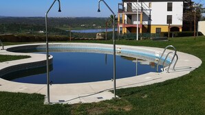A swimming pool with a geometric tile design, surrounded by a concrete deck and metal railings.