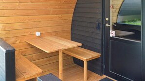 A wooden bench and table outside a building with a black door and a no smoking sign.