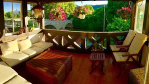 Un espace extérieur accueillant, doté d’une terrasse en bois, de sièges confortables et de suspensions florales.