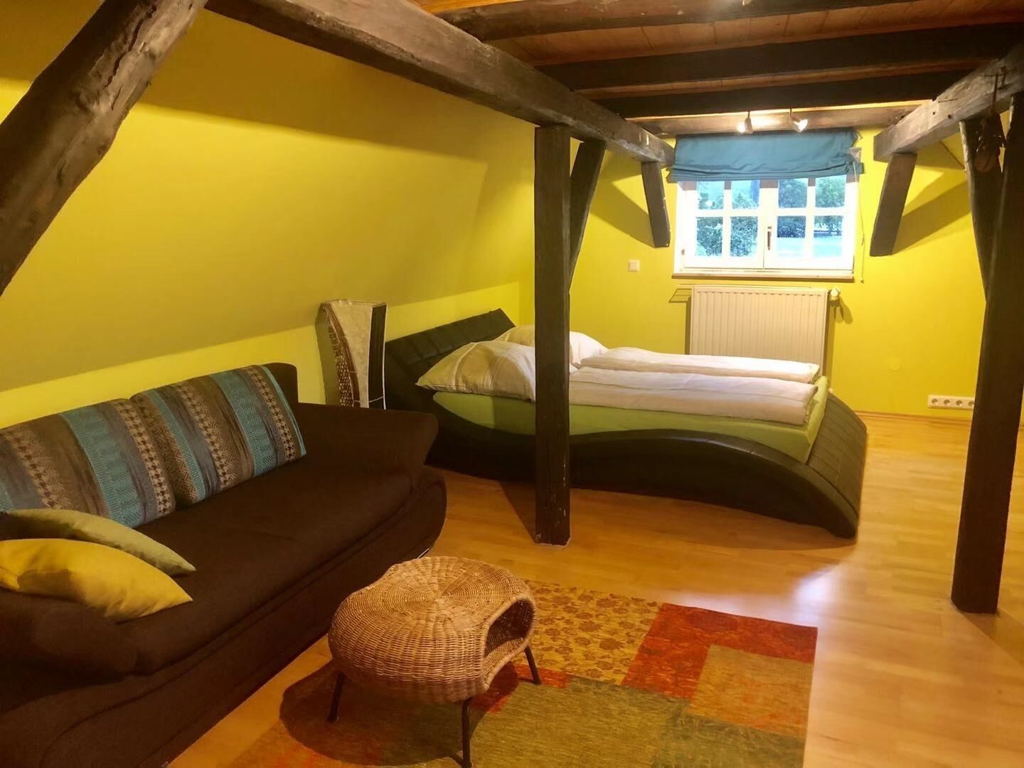 Ein gemütliches Schlafzimmer im Dachgeschoss mit einem Bett, einer Couch und einem kleinen Stuhl.