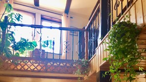 Un vaste espace de vie agrémenté d’un escalier en bois, d’une porte vitrée donnant sur l’extérieur et d’un chat assis près de la porte.
