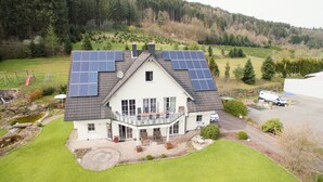 A house with solar panels on the roof, a garden, and a parking area. - Vacation home/event location, 285 m² living area, 300 m² secluded outdoor area  (Rieneck)