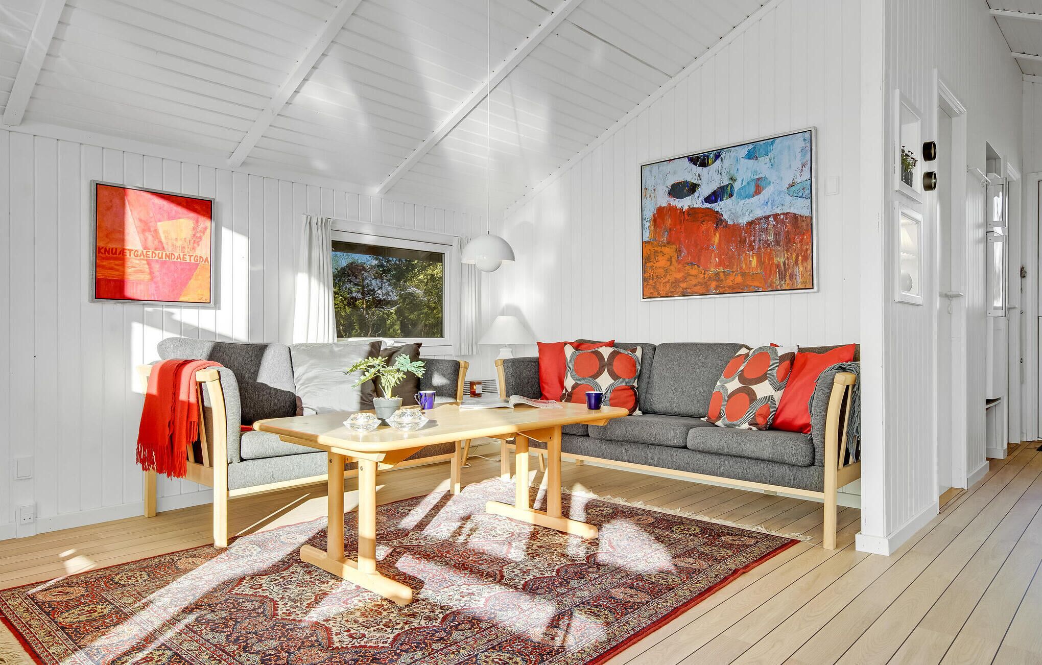 En moderne stue med en grå sofa, et træbord og et mønstret tæppe.