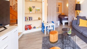 Een moderne woonkamer met een televisie, een boekenkast, een eethoek en een slaapkamer.